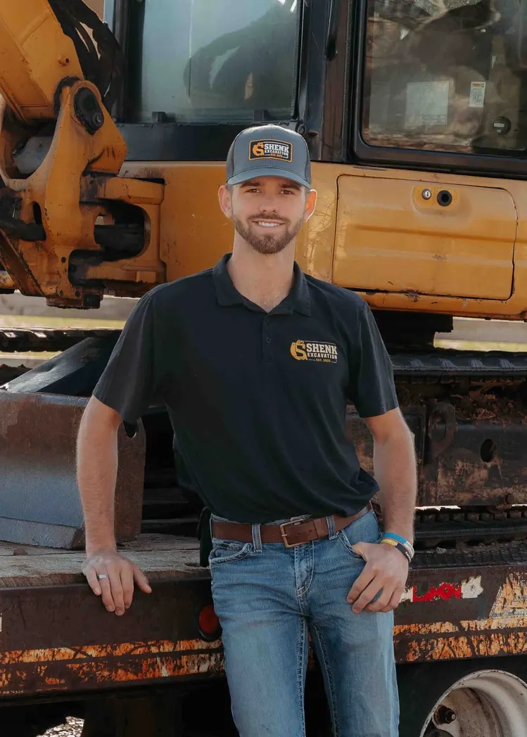 Shenk Excavation owner standing beside one of the company excavators