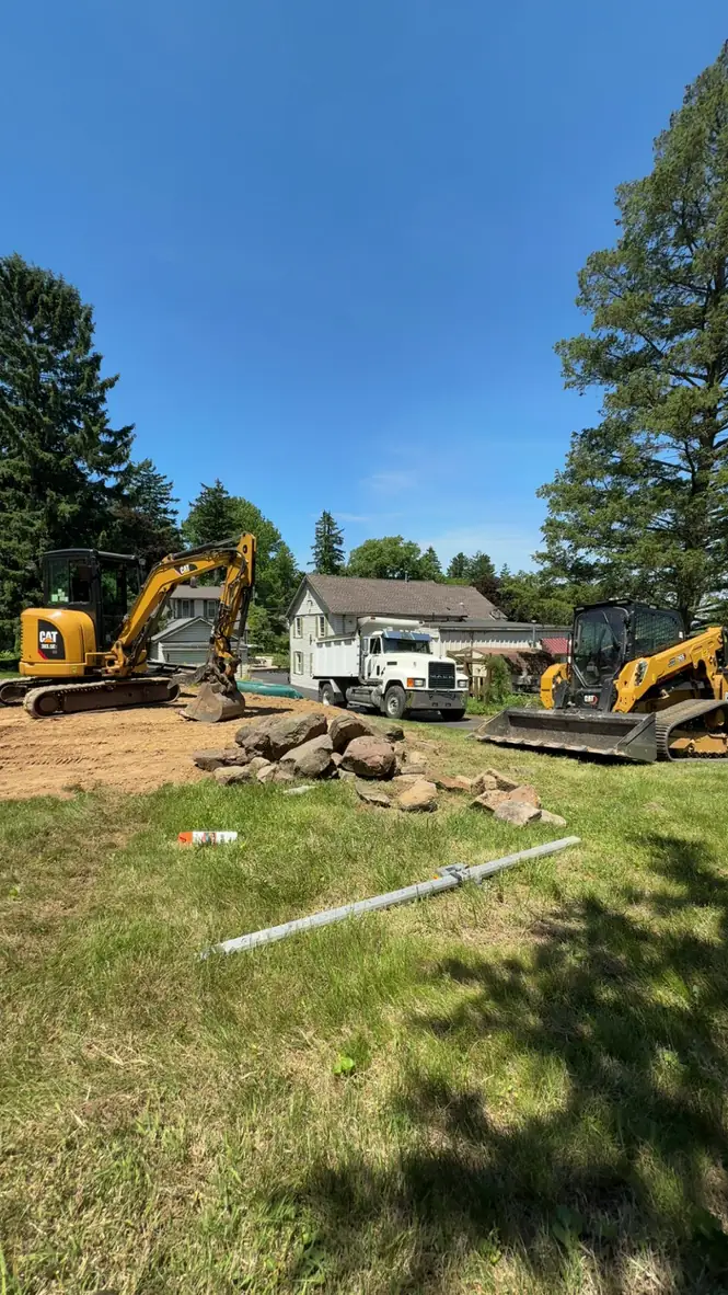 Excavator and dump truck staged on a residential lot