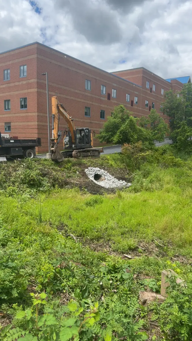 Excavator installing a drainage culvert